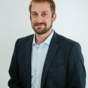 Cody Arendt headshot. Cody wears a dark blazer over a light-colored button-up shirt.