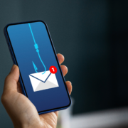 Hand holding a phone with an envelope on a hook.